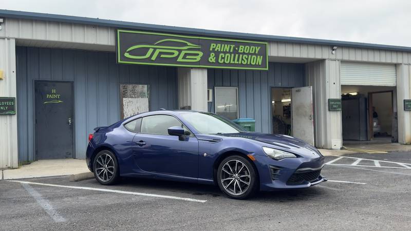 Blue Toyota 86 coupe parked under the JPB Paint Body & Collision sign