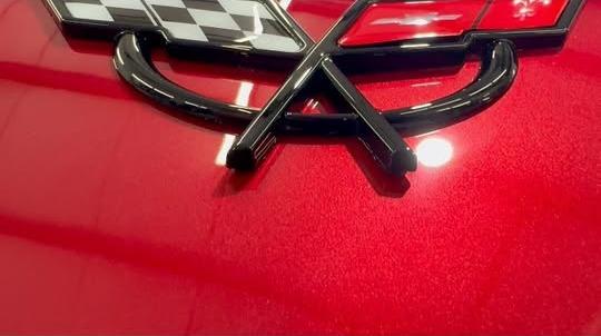 Corvette crossed-flags emblem on freshly polished red paint
