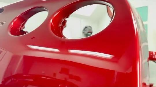 Freshly painted red Corvette rear bumper with a mirror gloss in a white paint booth
