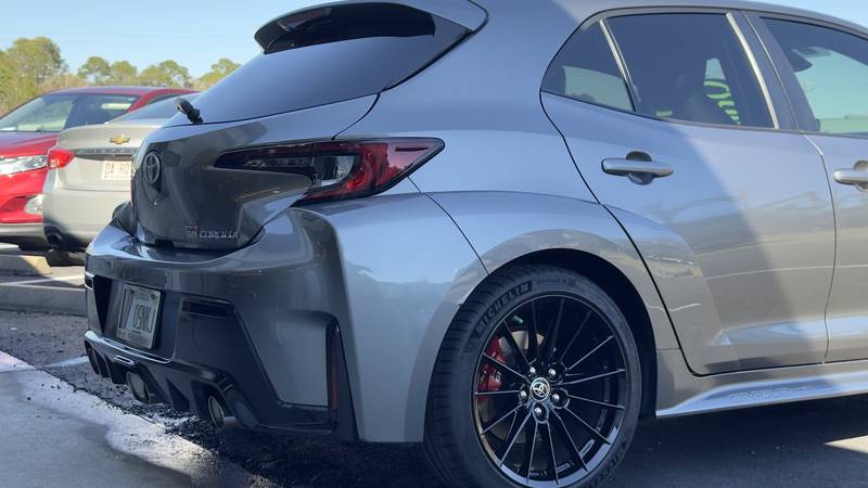 Rear quarter panel, door and black wheel of a gray Toyota GR Corolla