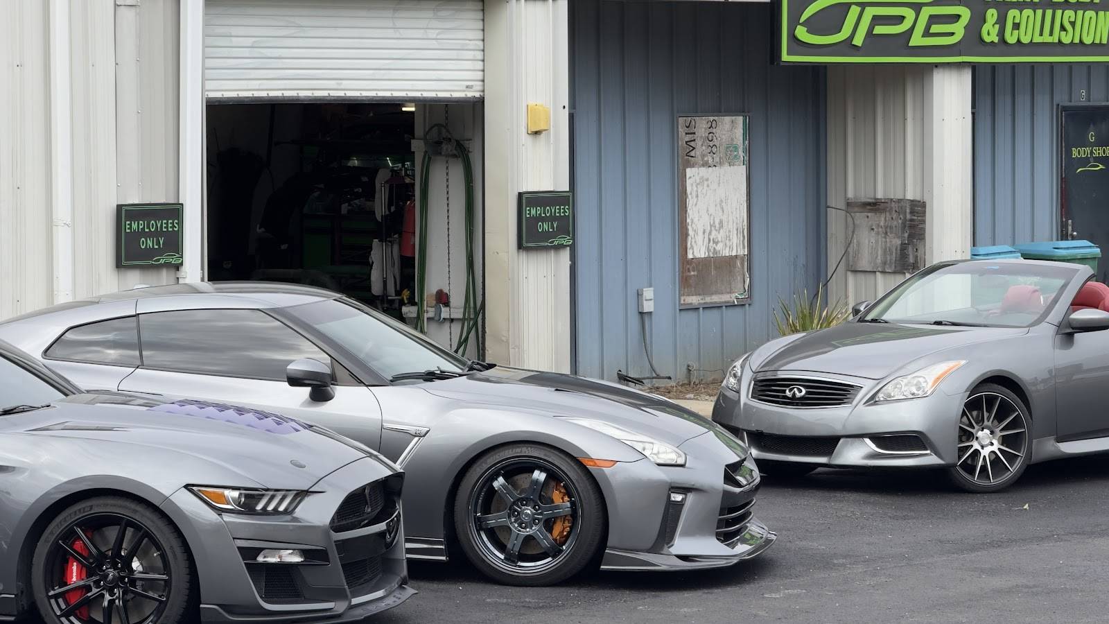 Gray Shelby Mustang, Nissan GT-R and Infiniti convertible parked at the open bay door of the JPB shop