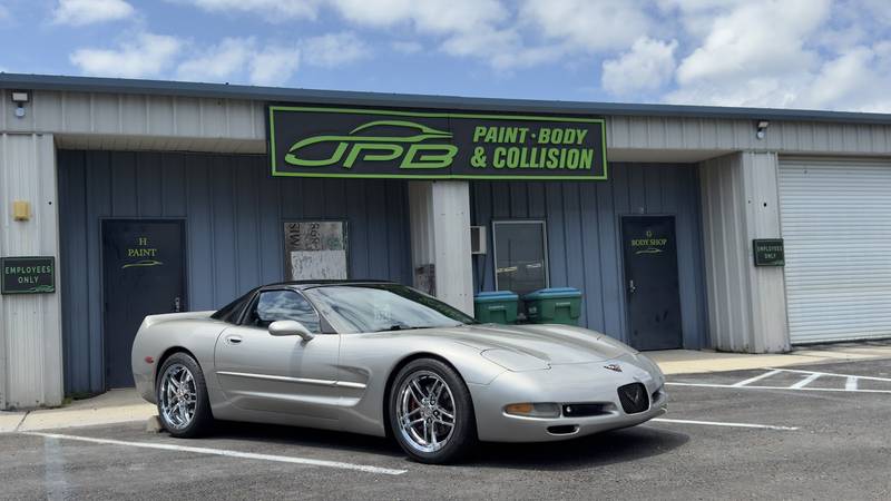 Silver Corvette parked in front of the JPB Paint Body & Collision shop